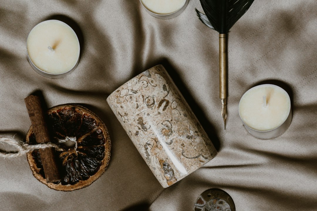 Composizione illustrativa con candele e penna d'oca. Foto di Emily Underworld su Unsplash; non documenta il rito che sarà eseguito su ordinazione.