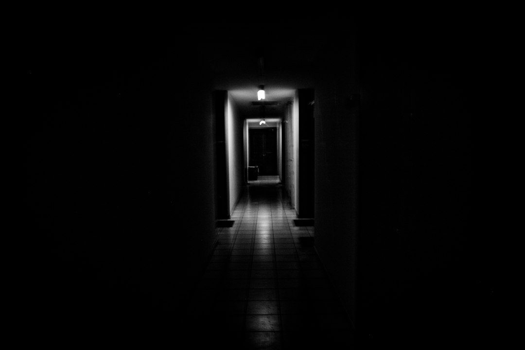 Corridoio in ombra con luce in fondo, immagine simbolica della possibilità di uscire dallo sfruttamento. Foto MARIOLA GROBELSKA, Unsplash.