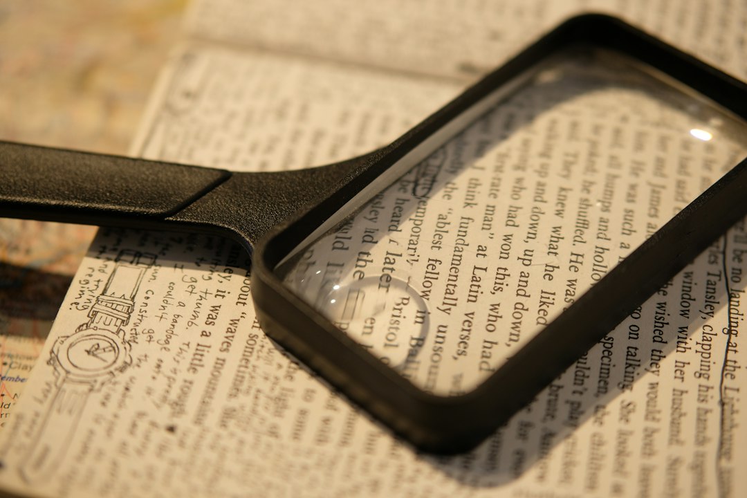Lente d'ingrandimento appoggiata su testo stampato: immagine illustrativa della verifica delle informazioni, foto di Spencer Liao su Unsplash